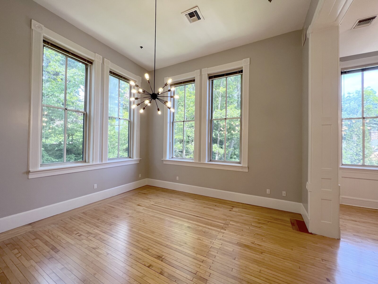 Sunlit bedroom corner with tall historic windows