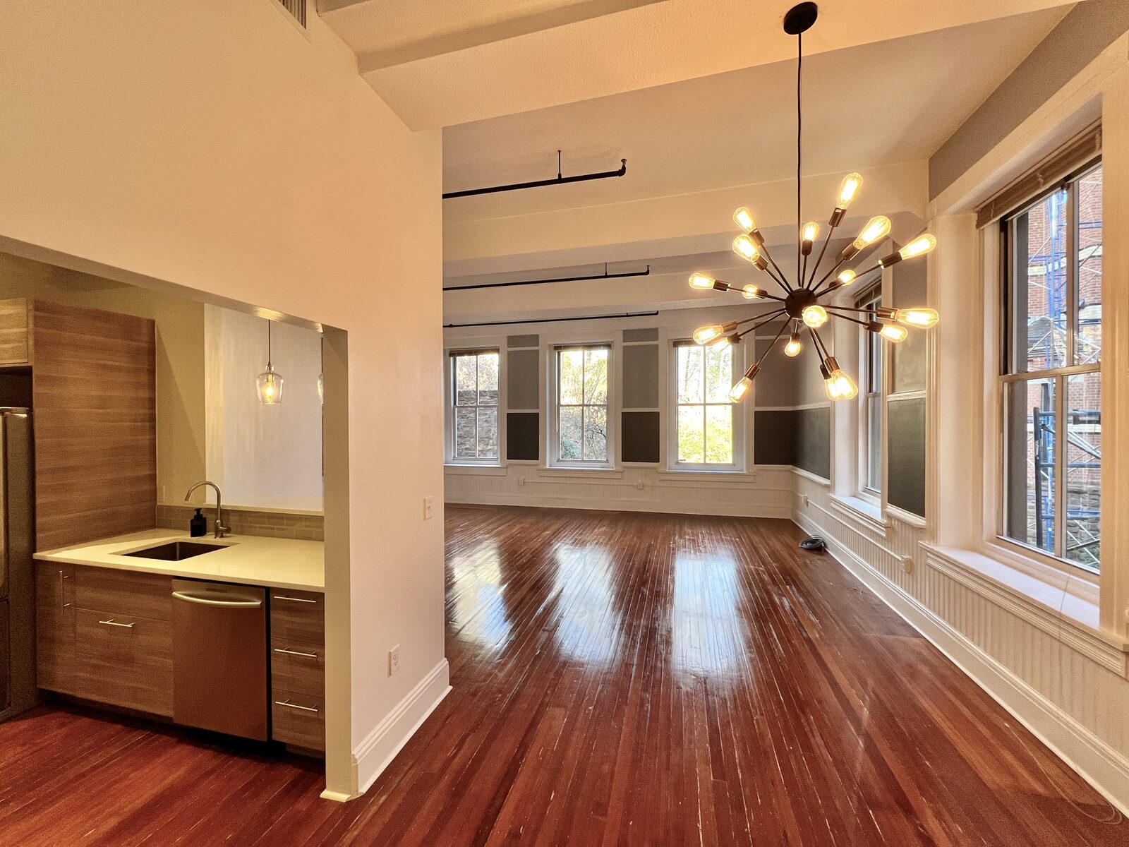 Two-bedroom residence living and dining area with rich hardwood floors and exposed brick