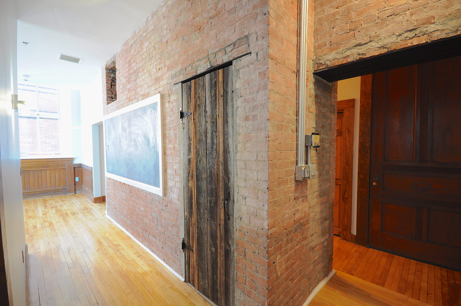 Original 1882 slate classroom chalkboard preserved in an exposed-brick hallway