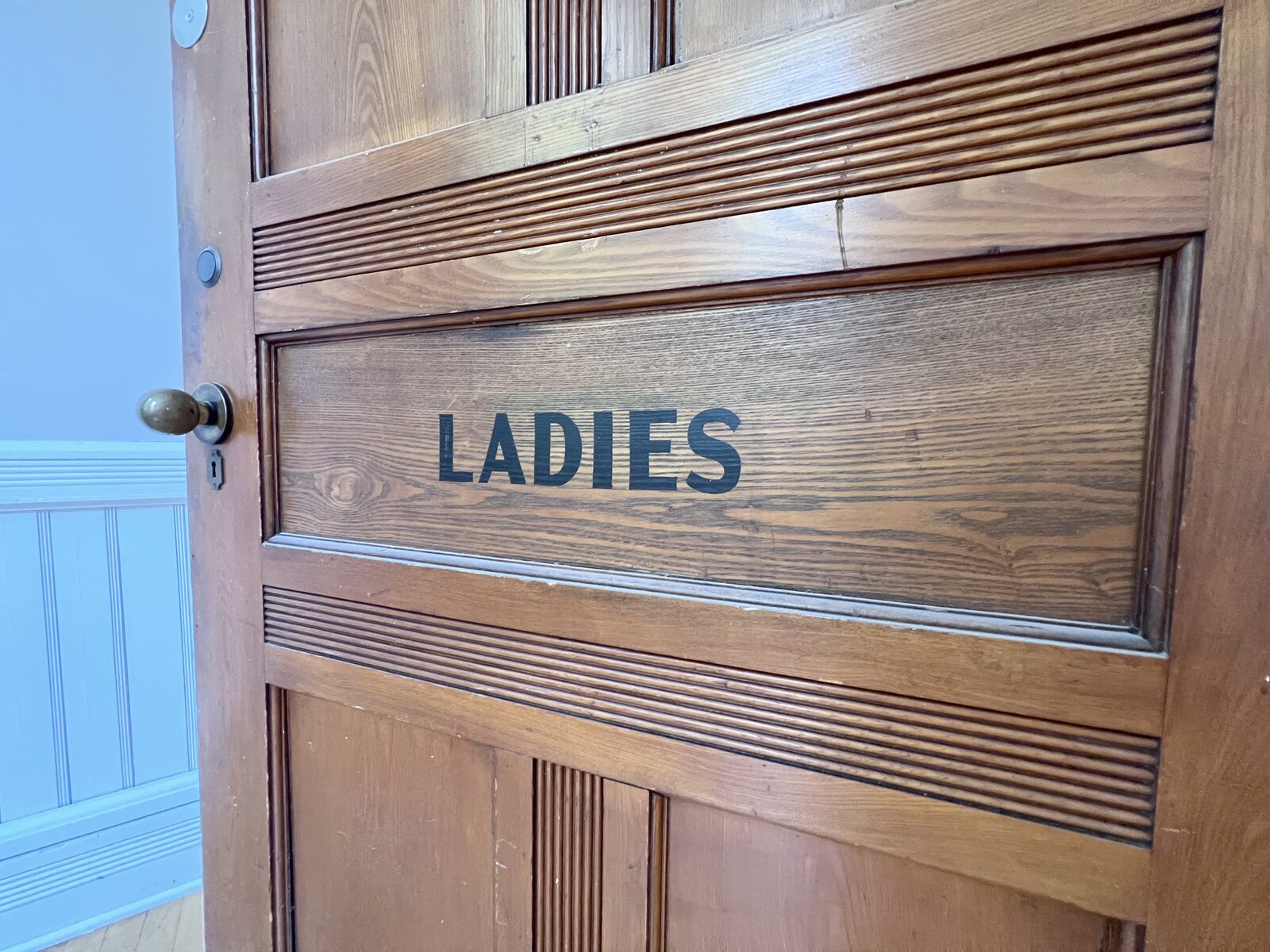 Original wood door reading 'Ladies', preserved from the building's school years